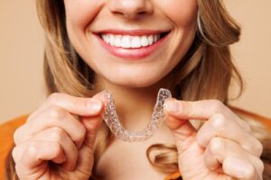 Woman smiling and holding Invisalign braces